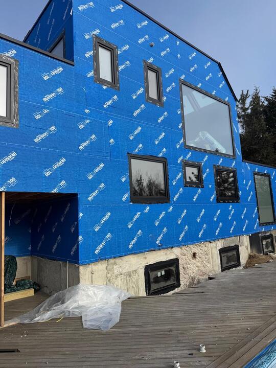 Black windows on a weather-wrapped new build