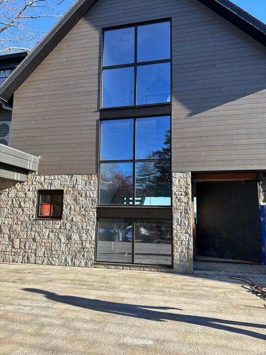 Tall black-framed windows beside a stone wall